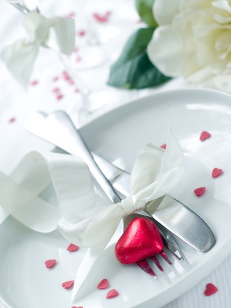 Fork and knife laying on plate with ribbon and heartの写真素材