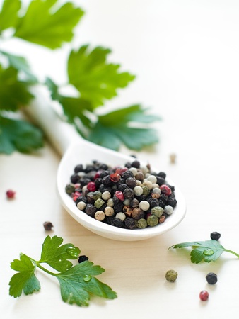 various pepper in wooden spoon with parsley on background の写真素材