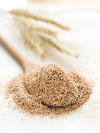 Oat bran in wooden spoon on kitchen towelの写真素材