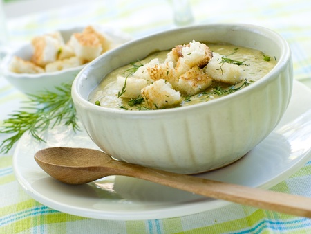A bowl of green vegetable soup with croutons and dillの写真素材