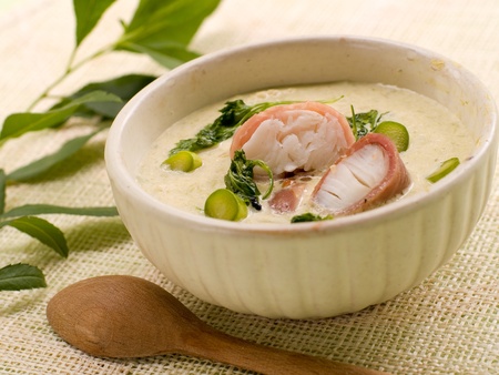 A bowl of asparagus creamy soup with fish, bacon and parsleyの写真素材