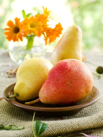 Fresh juicy pears on plate with flower on background. Selective focus の写真素材