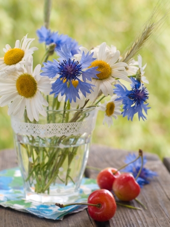 Wild flowers in glass with cherry, selective focusの写真素材