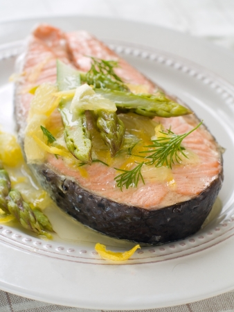 Steamed salmon with asparagus and lemon on white plate, selective focusの写真素材