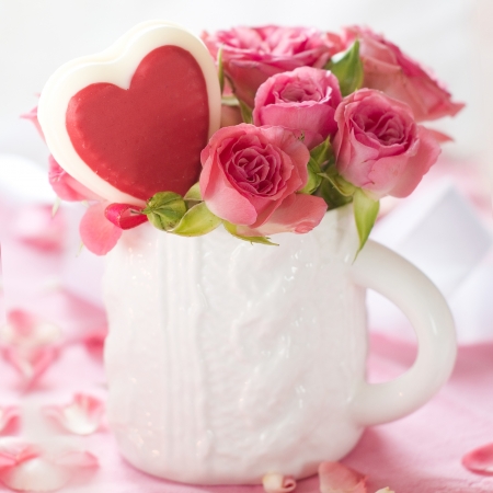 Pink roses in white cup with lollipop  for celebrationの写真素材