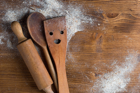 Wooden spoon, rolling pan and spatula on wooden background, selective focus. Cooking course poster background - layout with free text space.の写真素材