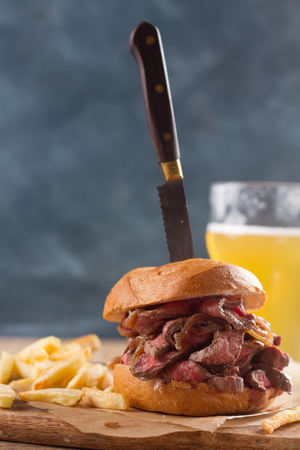 Tasty steak burger on a wooden board with potatoes and dipping sauce, selective focusの写真素材