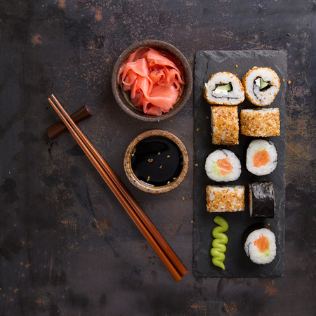 Sushi rolls set with marinated ginger, soy sauce and wasabi on stone background, selective focusの写真素材