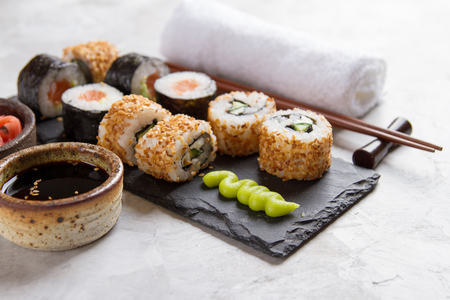 Sushi rolls set with marinated ginger, soy sauce and wasabi on stone background, selective focusの写真素材