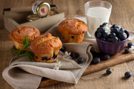 Homemade blueberry muffins with glass of milk  and fresh berries on wodden background, selective focusの写真素材