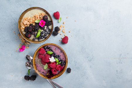 Breakfast berry smoothie bowl topped with blueberries, raspberry, blackberry, chia seeds, oat flakes and muesli for healthy breakfast, selective focusの写真素材