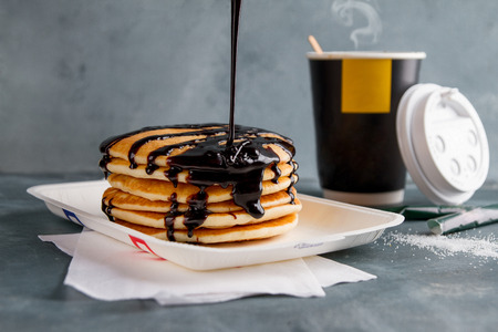 Stack of american pancakes or fritters with chocolate sauce and coffee for breakfast, selective focusの写真素材