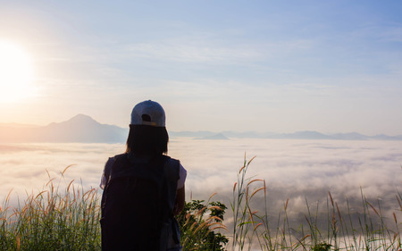 Young Woman standing alone outdoor with wild forest mountains on background Travel Lifestyle and survival concept rear view,Woman spreading hands with joy and inspiration in mountains.の写真素材