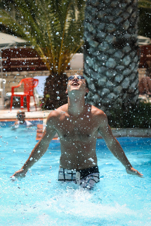 Picture of a young man in the swimming pool splashing waterの写真素材