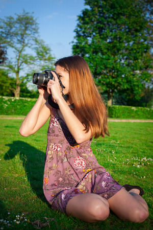 Girl with the camera in the park smiling and looking happyの写真素材