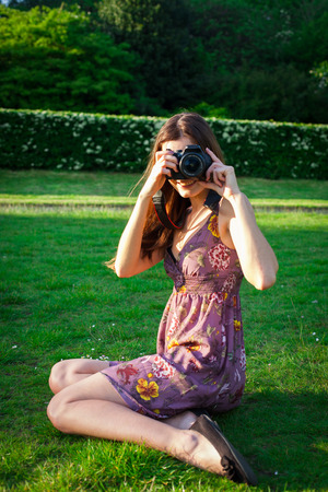 Girl with the camera in the park smiling and looking happyの写真素材