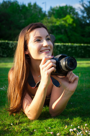 Girl with the camera in the park smiling and looking happyの写真素材