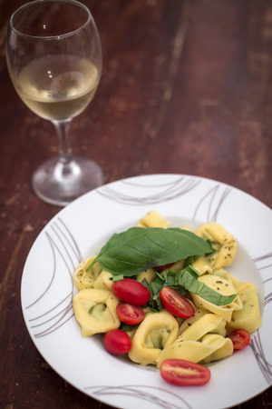 Ravioli with tomatos and basil and white wine on the tableの写真素材