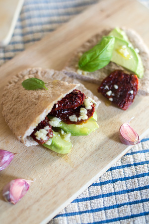 Pita bread with avocado and sundried tomatoes on the wooden boardの写真素材