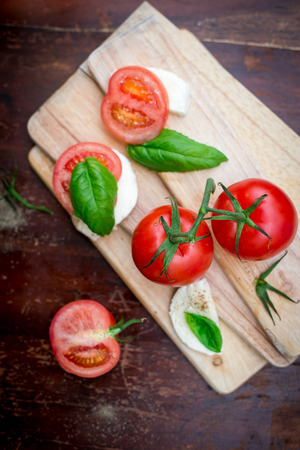 Tomatoes, mozarella and basil on the tableの写真素材
