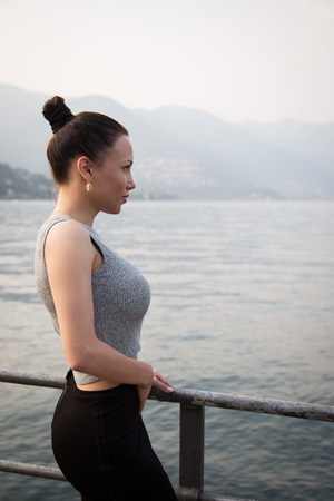 Young beautiful woman standing looking at the lakeの写真素材