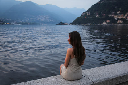 The young woman looking at the beautiful view at the lakeの写真素材