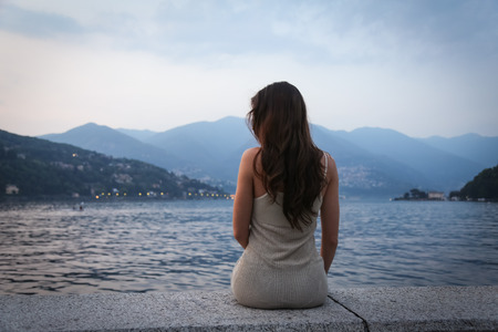 The young woman looking at the beautiful view at the lakeの写真素材