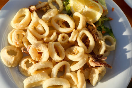 Fried calamari rings with lemon on the plate natural lightの写真素材