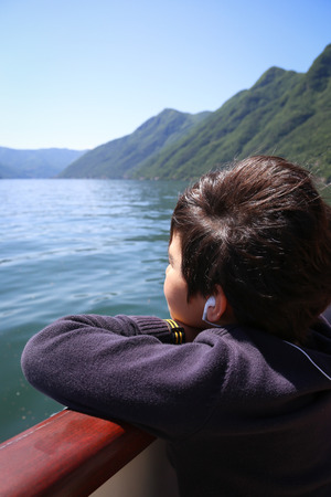 Little boy on the boat tour looking at the views at the lake Comoの写真素材