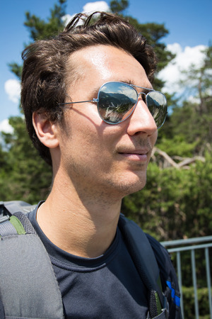 Portrait of a young traveller looking at the mountains with reflection in his sunglassesの写真素材