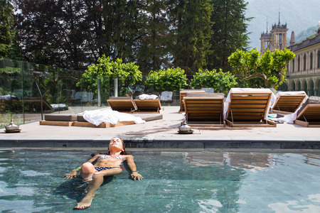 Young woman relaxing in the swimming pool with beautiful view on the backgroundの写真素材