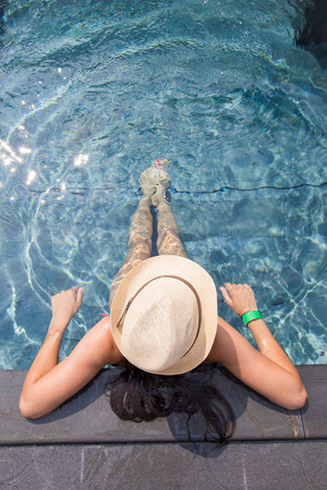 View from the top of a girl in a hat relaxing in the swimming poolの写真素材