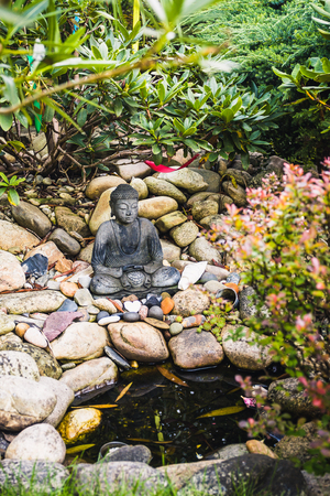 Little statue of the meditating buddha in the gardenの写真素材