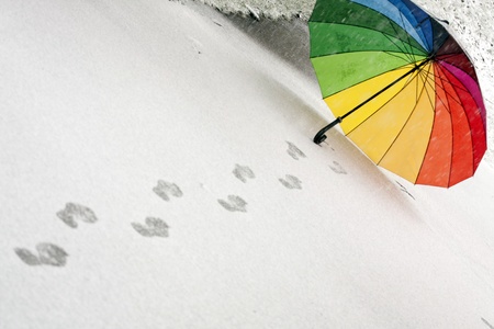 Colorful umbrella in the fresh fallen snow with some footprints around it.の写真素材