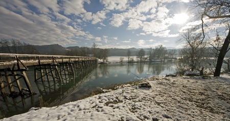 Winter landscape by the river with wooden bridge.の写真素材