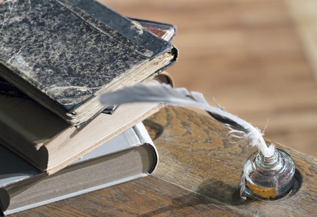 Old school table with book, ink and feather pencil.
