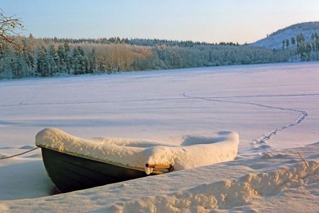 boat under snow on a frozen lakeの写真素材
