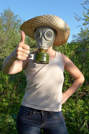 woman in gas-mask on garden background with "all right" sign of handの写真素材