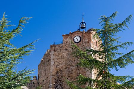tower of old Spanish fortress with big bell, weather vane and clockの写真素材