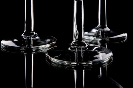 three wineglasses bottoms on mirrored surface, isolated on blackの写真素材