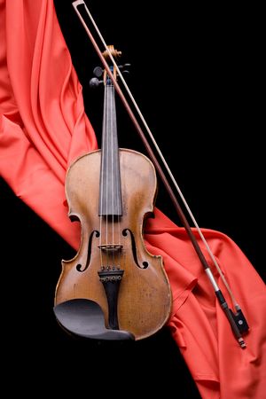 old violin with fiddlestick on folded scarlet silk diagonal on black backgroundの写真素材