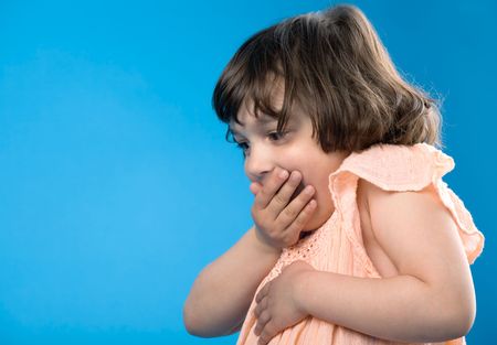 toddler girl with surprised emotional face isolated on blue, there is empty space in left corner of imageの写真素材