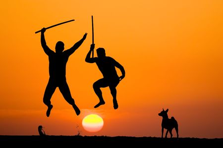 silhouette of two flying warriors with swords in hands on sunsetの写真素材