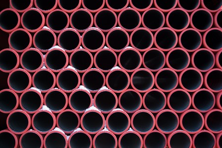 pattern of red pipes with snow stacked in construction siteの写真素材