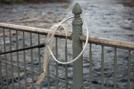 landing net hanging on grey iron  fencing over the water