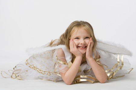beautiful little girl in suit butterfly with wings holds palms about  person and lie on floorの写真素材