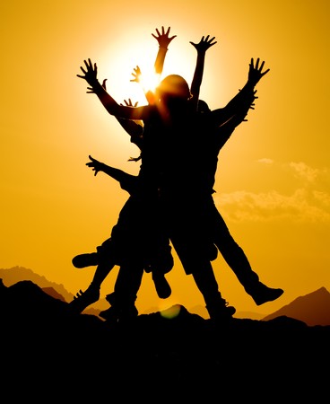 black silhouette of people group in happy jump on orange sunset sky and desert mountain backgroundの写真素材