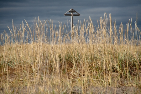 wooden Christian cross on dry grass and dark cloudy sky backgroundの写真素材