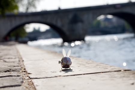small funny clockwork toy hare on Seine embankment and bridge background, Paris
