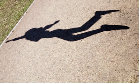 black figure silhouette of human shadow in flying jumpの写真素材